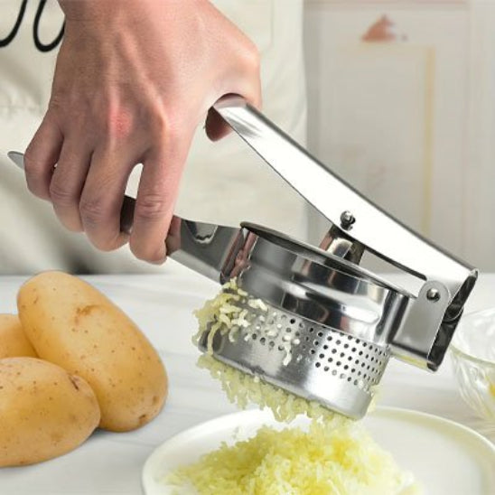 homme écrase pommes de terre dans assiette blanche utilisant presse purée manuel