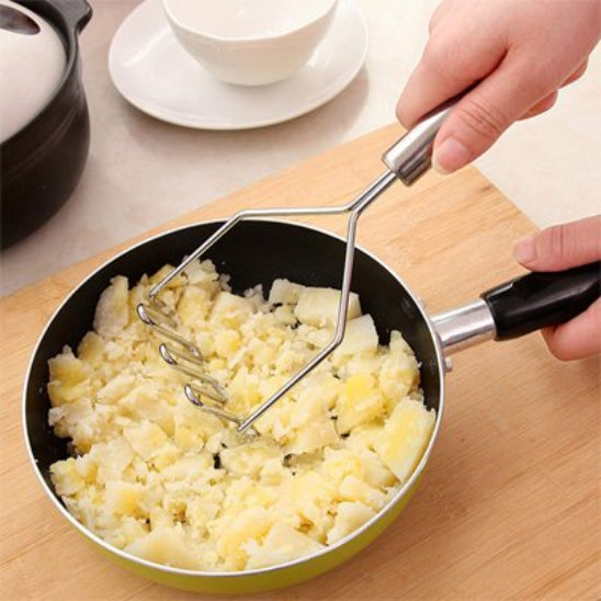 femme  écrase pommes de terre avec presse purée dans poêlon