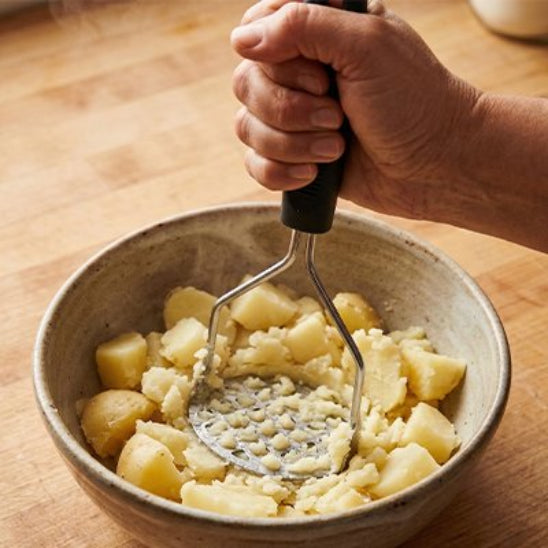 homme écrase pomme de terre dans bol céramique avec presse-purée