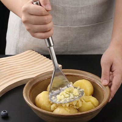 homme écrase pommes de terre dans bol céramique utilisant presse purée
