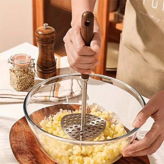 cuisinier écrase pommes de teere avec resse-purée