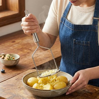 femme écrase pommes de terre dans bol avec presse purée