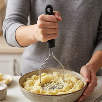 femme  écrase pomme de terre dans bol céramique avec presse-purée