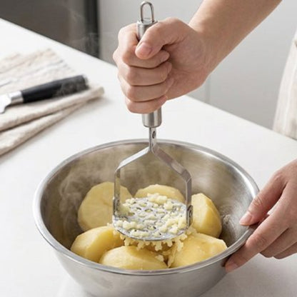 femme écrase pommes de terre dans bol en inox avec presse purée 