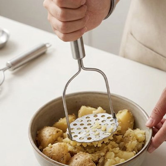 homme écrase pommes de terre dans bol avec presse purée