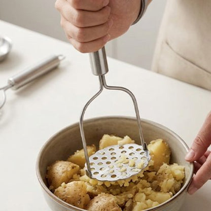 homme écrase pommes de terre dans bol avec presse purée