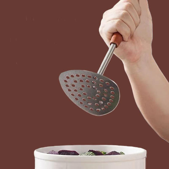 presse-purée au dessus d'un bol de légumes blanc