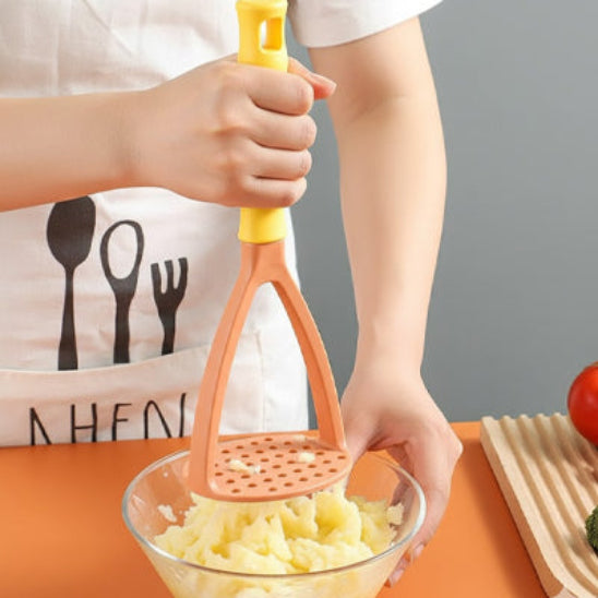 un jeune écrase pommes de terre dans bol en verre avec un presse purée orange orange