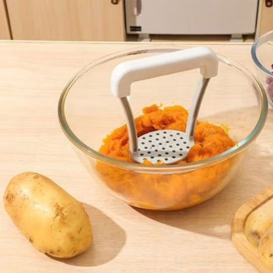Presse purée dans bol en verre contenant carrottes écrasées 