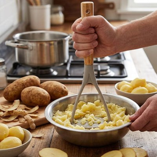 homme pile pommes de terre dans bol inox sur compltoir bois utilisant presse-purée