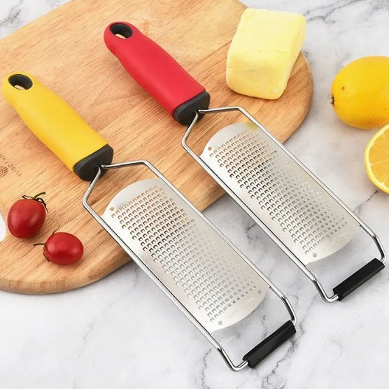une ràpe à fromage a poigné rouge et une jaune sur planche à découper