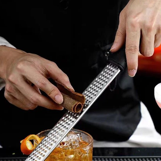 cuisinier râpe  cannelle dans cocktail avec râpe à fromage 