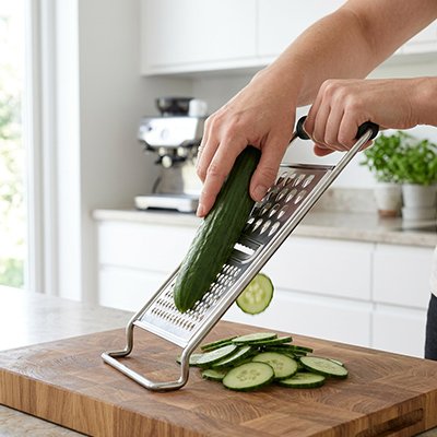 Râpe à légumes manuelle posée sur planche à découper râpe cocombre