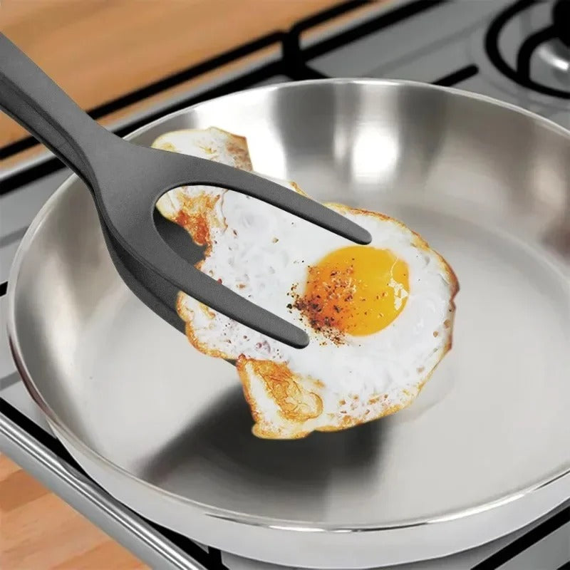 spatule-pince-noire-saisit-un-oeuf-d-une-poêle-inox