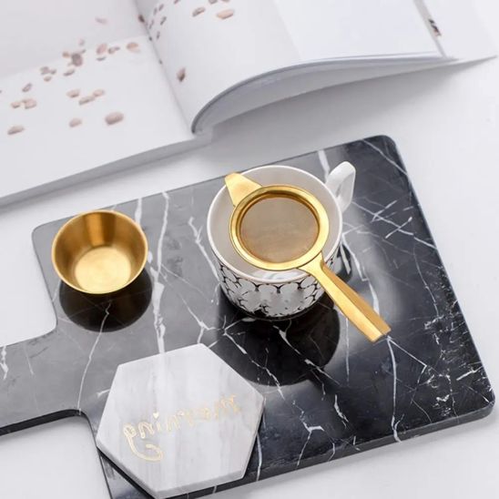 tamis or dans tasse avec coupe à côté sur planche marbre noir