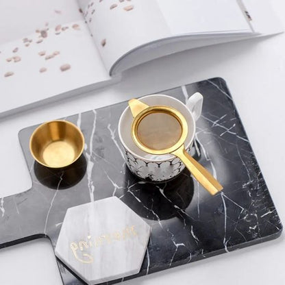 tamis or dans tasse avec coupe à côté sur planche marbre noir