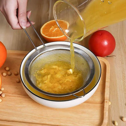femme filtre jus d'orange avec tamis cuisine inox