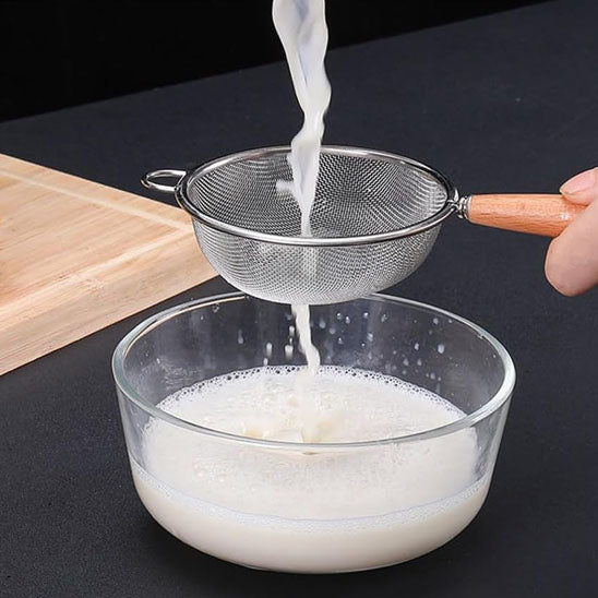 lait-filtré-avec-un-tamis-inox-à-manche-en-bois