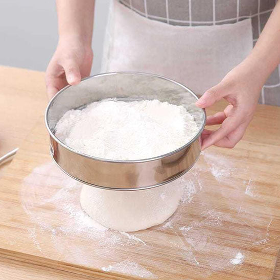 cuisinère-utilise-tamis-rond-inox