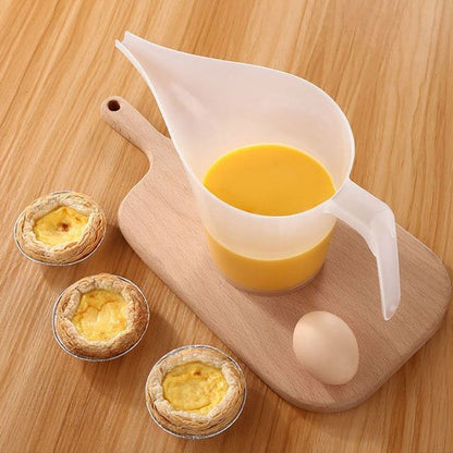Verre doseur à bec long sur planche à découpter  à côté de trois tartellettes