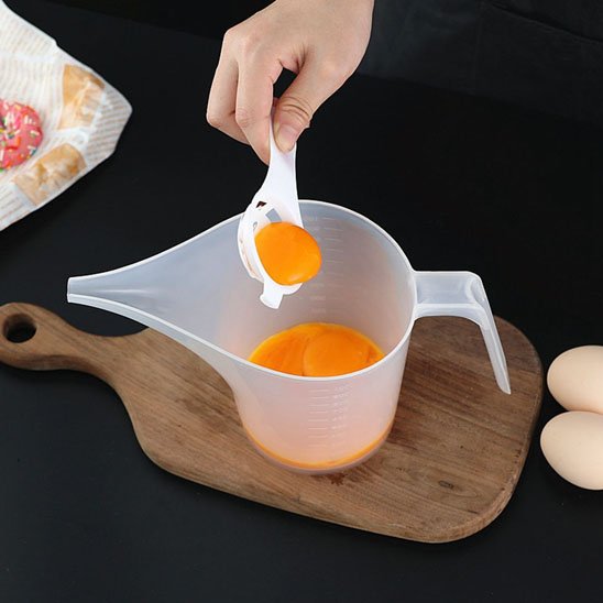 cuisinier verse jaune d'œuf dans verre doseur