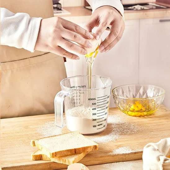 femme casse œuf dans verre doseur