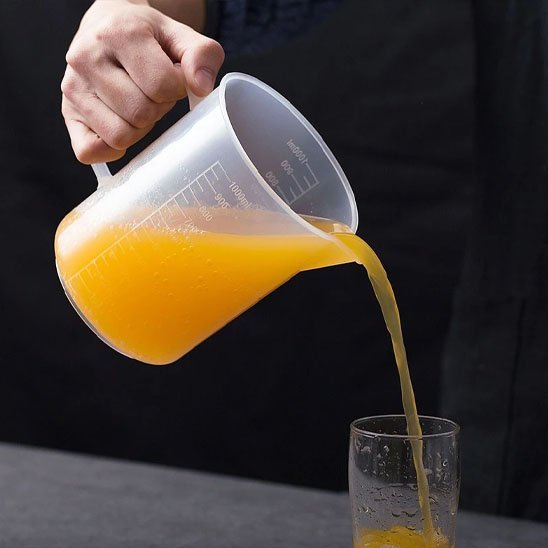 homme verse jus du verre mesureur dans un verre.