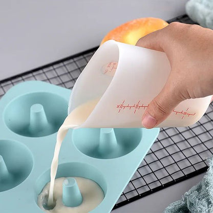 cuisinière verse pâte du verre mesureur dans moule a beignets