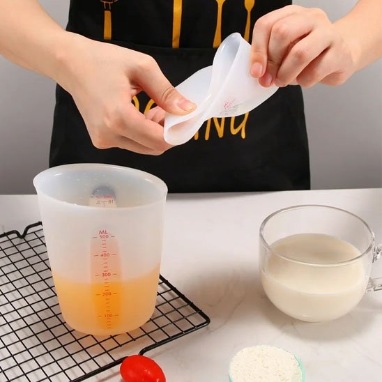 femme fait preuve de souplesse du verre mesureur à côté d'un autre sur comptoir cuisine